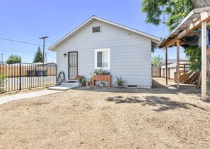 A single-story house with a front porch, a small garden with potted plants, and a wooden fence.