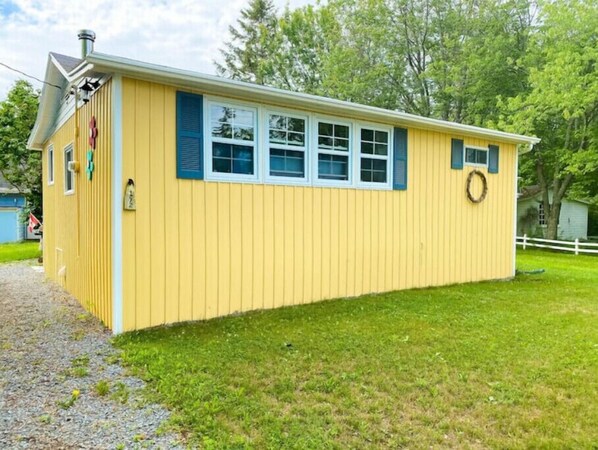 A yellow single-story building with a small porch, a chimney, and a wreath on the door. - Cottage at Evangeline Beach & near Local Wineries (Grand Pré)