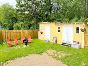 Enjoy a serene outdoor space with a charming shed, Adirondack chairs, and a lantern.