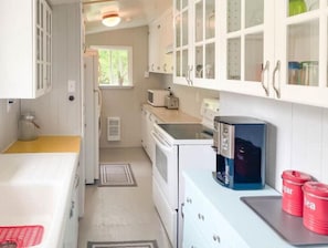 Compact kitchen with a stove, microwave, and toaster oven, featuring a small window and ample counter space.