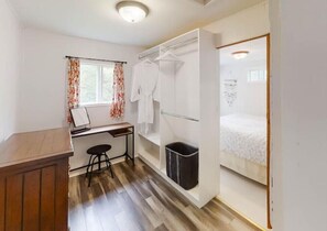 A compact room with a wooden desk, a chair, a bed, and a wardrobe. - Cottage at Evangeline Beach & near Local Wineries (Grand Pré)