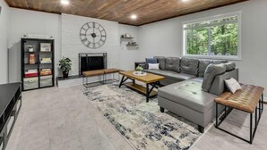 Een moderne woonkamer met een open haard, een groot klok, een bank, een salontafel en een boekenkast.