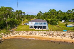 A beachfront house with a large deck and a covered porch.