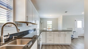 Eine moderne Küche mit weißen Schränken, Granit Arbeitsplatten und einer Edelstahlspüle.