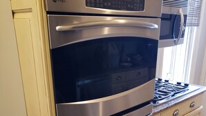 Una estufa de acero inoxidable con panel de control digital, horno integrado y superficie de cocción.