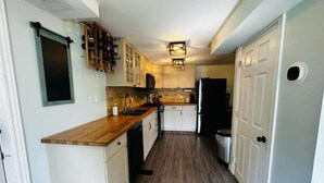 A compact kitchen with white cabinets, a wooden countertop, and a black refrigerator.