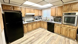 Une cuisine avec des meubles de rangement en bois, un réfrigérateur noir, un lave-vaisselle, un four à micro-ondes et un grille-pain.