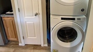 A laundry room with two stacked front-loading washing machines. - Tiny Farmhouse | CDA, Silverwood & Lake Nearby (Coeur d'Alene)