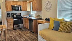 A compact kitchen with wooden cabinets, a microwave, stove, and dishwasher. - Tiny Farmhouse | CDA, Silverwood & Lake Nearby (Coeur d'Alene)