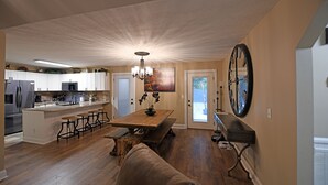 A spacious kitchen with a wooden island, bar stools, and a dining table. - Two Homes in One! Bear Hollow is the Perfect Luxury Escape for Large Gatherings! (Sevierville)