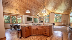 Una cocina amplia con una isla grande, armarios de madera y una chimenea de piedra.