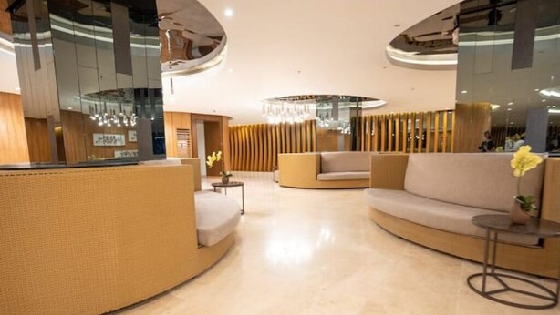 Een moderne lobby met een gebogen receptiebalie, een zithoek en een kroonluchter.