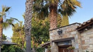 A stone building with a wooden door, potted plants, and a stone pathway. - Ktima Zotos _ Luxury Exotic Cottage 1 (Volos - Pelion) (SOUTRALI AGRIA)