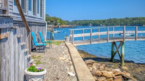 A wooden dock extending into a calm body of water, with a chair and potted plants on the dock's edge. - Linekin Lodge | Oceanfront | 3BDR| Deep Water Dock| Beach (Boothbay Harbor)