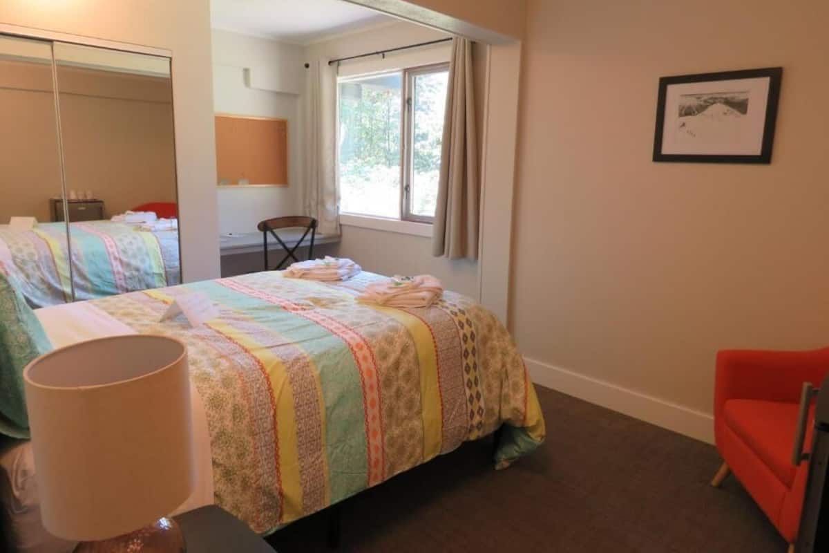 A bedroom with a bed, a chair, a lamp, a window, and a framed picture on the wall.