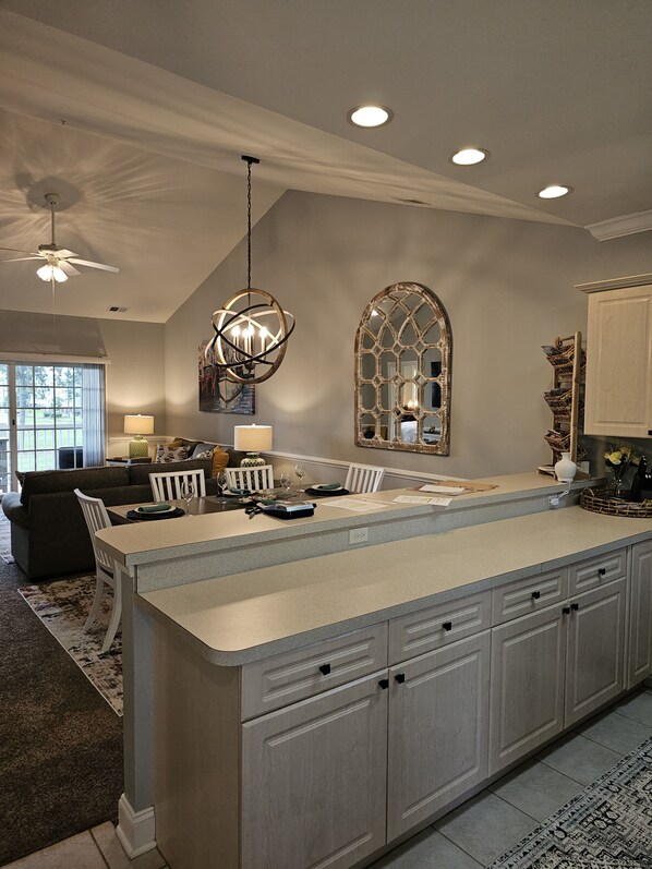 A spacious kitchen with a large island, pendant lighting, and a decorative mirror.