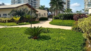 A residential area with modern buildings, a pathway, and well-maintained greenery. - Nautilus Paraíso Tropical - Vista ao Mar (Penha)
