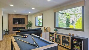 A modern living room with a pool table, a large TV, and a bookshelf. - Casitas Cueva del Gato Benaoján by Ruralidays (Málaga)