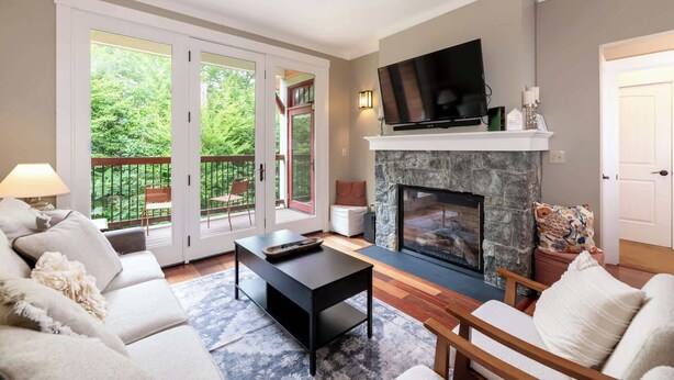 A living room with a fireplace, a sofa, a coffee table, and a television. - Riverfront Condo w/ Hot Tub | River Swimming Spot! (Lincoln)