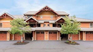 A multi-story building with a symmetrical facade, multiple garage doors, and a central entrance. - Riverfront Condo w/ Hot Tub | River Swimming Spot! (Lincoln)