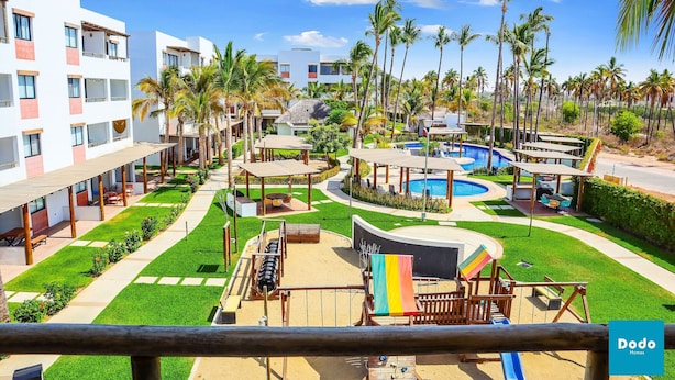 Un resort con piscina, mobiliario exterior y palmeras.