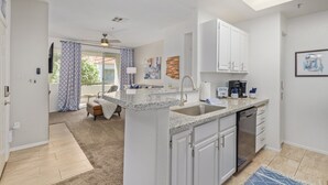 Una cocina moderna con gabinetes blancos, encimera de granito y lavavajillas integrado.