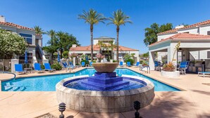 Un área de piscina con jacuzzi, sillas de descanso y palmeras.