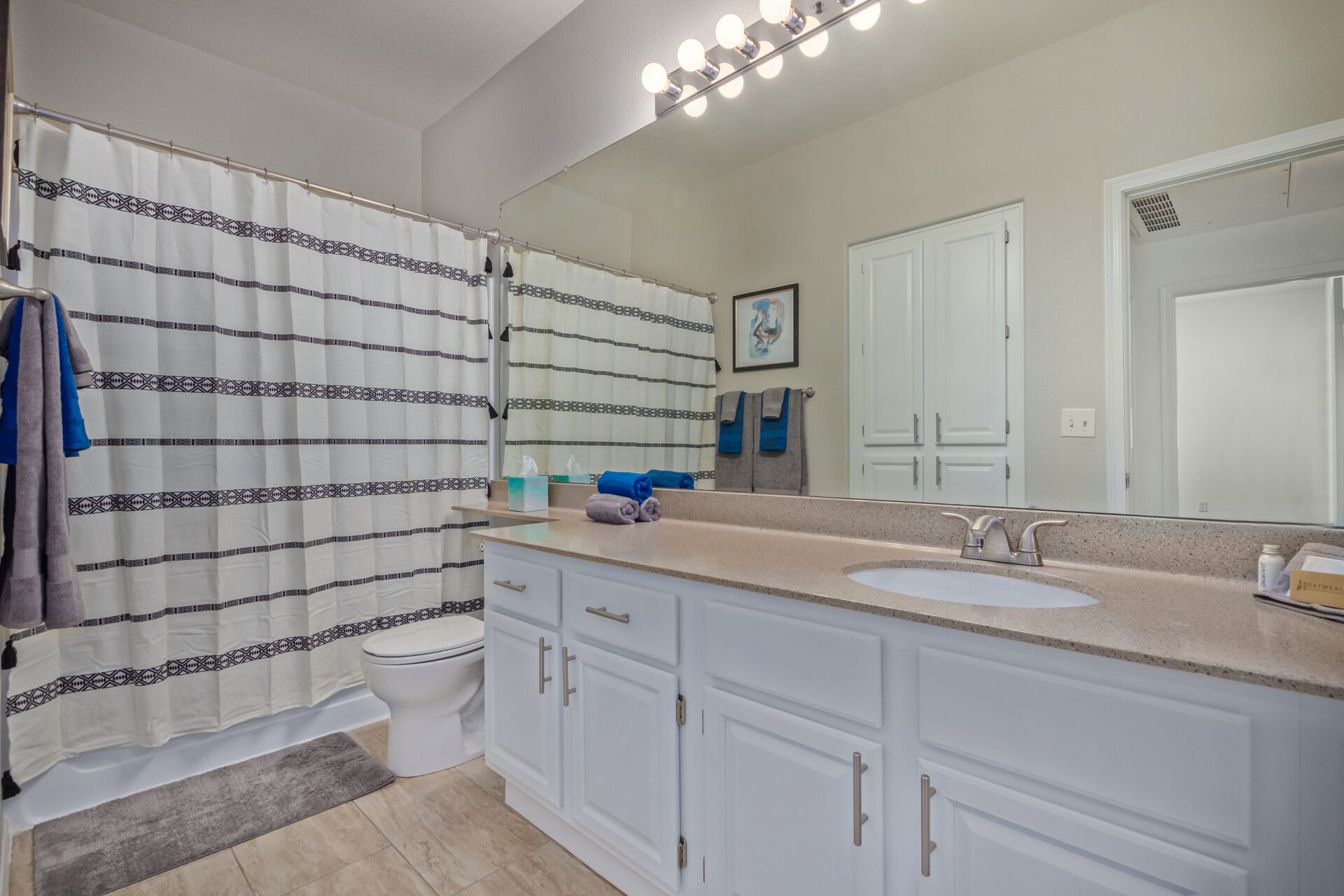 Une salle de bain avec un rideau de douche, un lavabo, un miroir et un porte-serviettes.