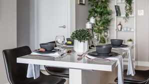 A dining table set with black bowls, wine glasses, and a potted plant.