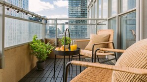 A balcony with wicker chairs, a small table with a glass of orange juice, and potted plants.
