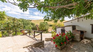 A rustic outdoor patio with a stone floor, a wooden fence, and a brick oven. - Cortijo Don Pablo Gaucín by Ruralidays (Málaga)