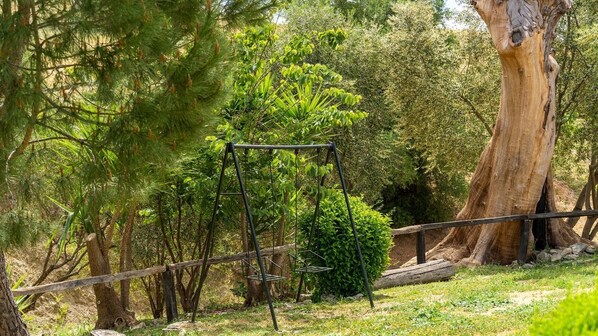 A swing set in a wooded area with a large tree trunk nearby. - Cortijo Don Pablo Gaucín by Ruralidays (Málaga)