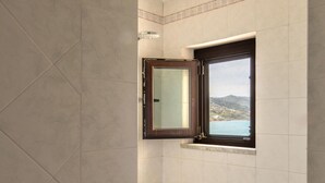 A bathroom with a window, tiled walls, and a shower area. - Meravigghia Apartment by Wonderful Italy (Cefalù)