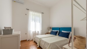 A hotel room with two beds, a desk, a lamp, and a basket on the desk.