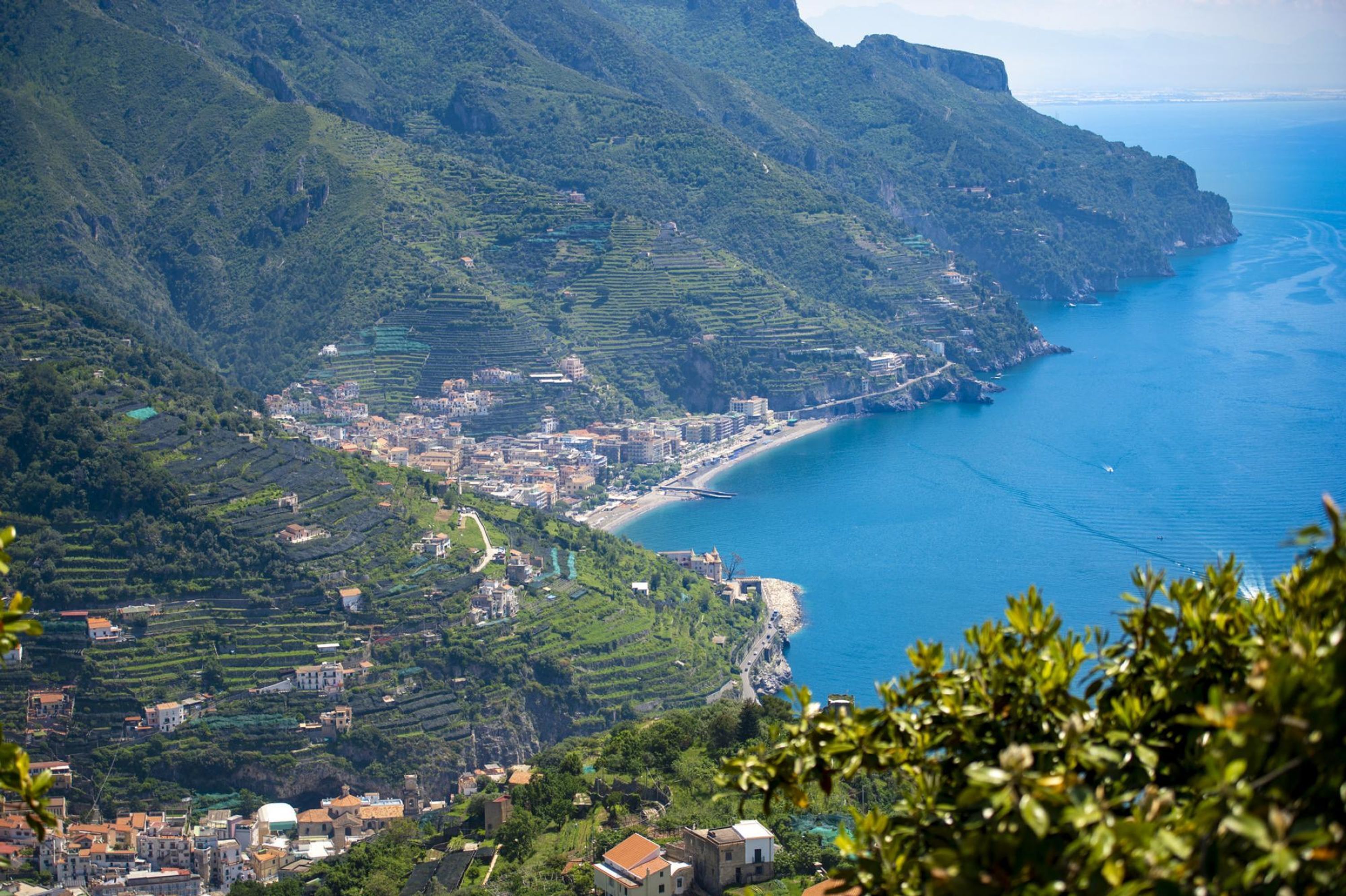 A coastal town with terraced vineyards, a beach, and a view of the sea.