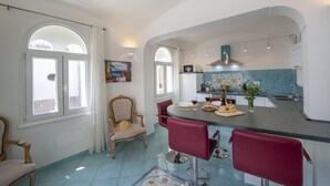 Un'ampia cucina con zona pranzo, caratterizzata da una grande isola, sgabelli da bar rossi e una sedia tradizionale.