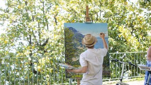 Una persona dipinge un paesaggio su un cavalletto all'aperto.