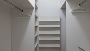 A narrow walk-in closet with white shelving units and a wooden parquet floor. - 5 Minutes From Leblon Beach Ap102 (Rio de Janeiro)