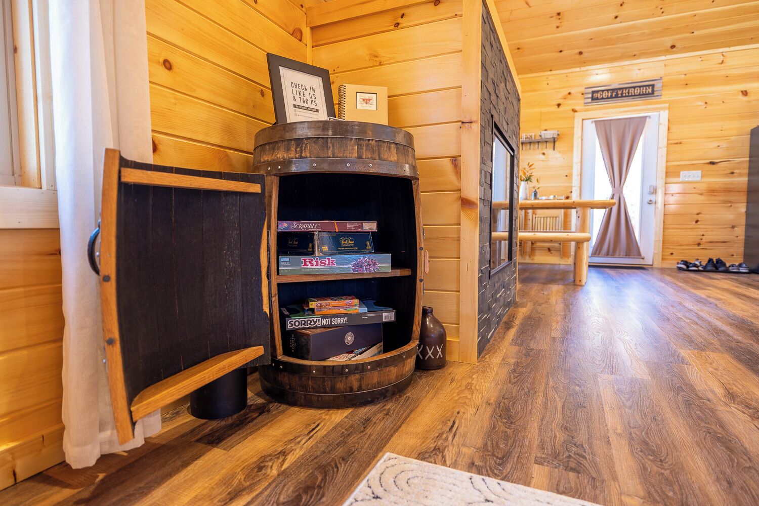 A wooden interior with a barrel shelf holding board games, a wooden bench, and a door labeled "COFFEE ROYAL".