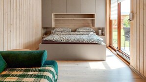 Ein Schlafzimmer mit einem Bett, einem Nachttisch, einem Stuhl und einem Fenster.