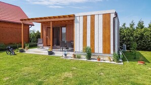 Eine Holzhütte mit überdachter Veranda, Sitzgelegenheiten im Freien und einem kleinen Garten.