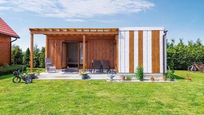 Eine Holzhütte mit überdachter Veranda, zwei Tischen und Stühlen.