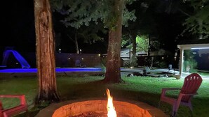 Un foyer avec des chaises, un arbre et une structure illuminée de lumière bleue en arrière-plan.