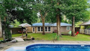 Un jardin avec une piscine, une maison et une cour clôturée.