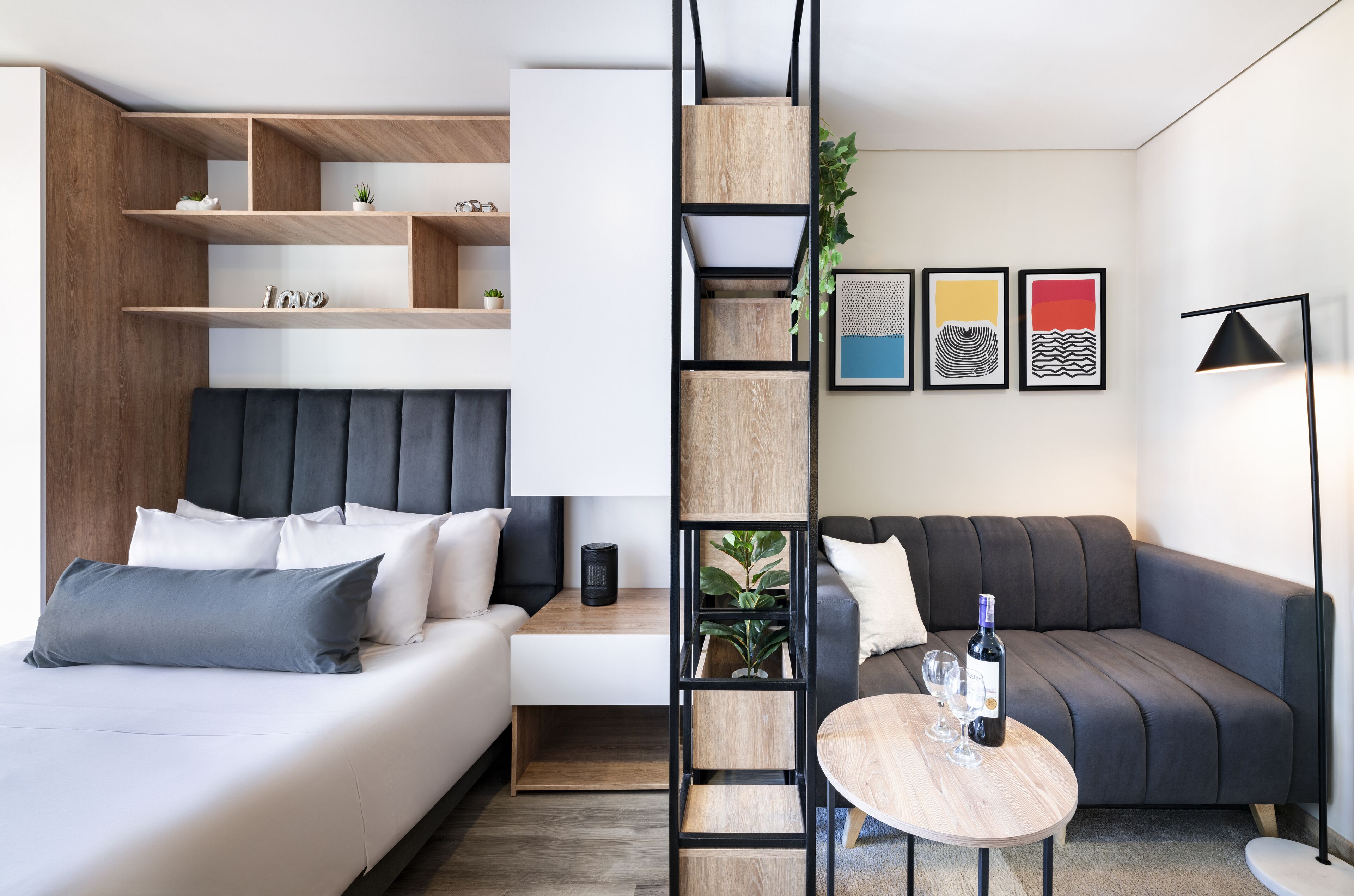 Un dormitorio moderno con cama, sofá, una mesita y estantería.