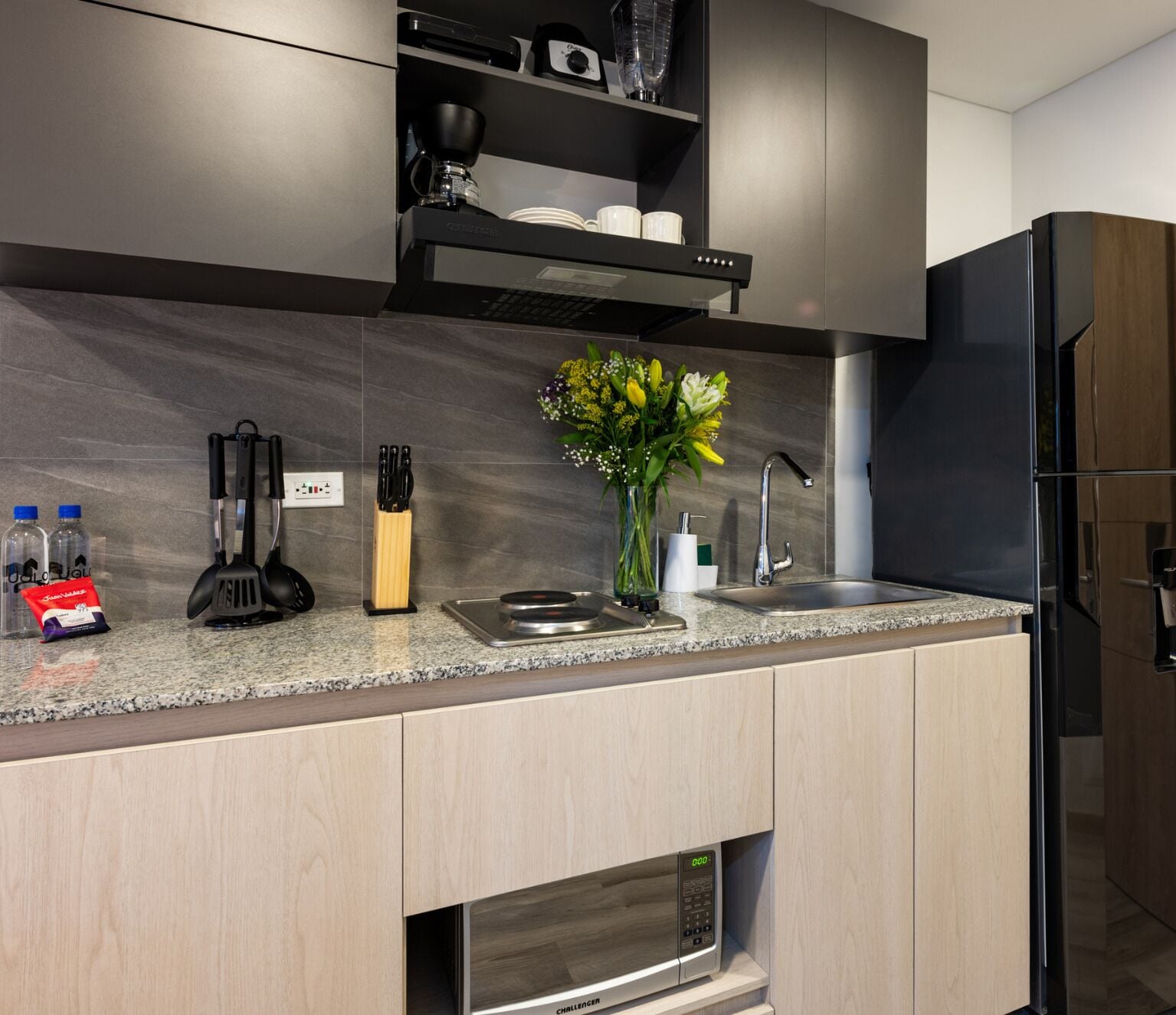 A modern kitchen with a built-in microwave, a coffee maker, and a sink.