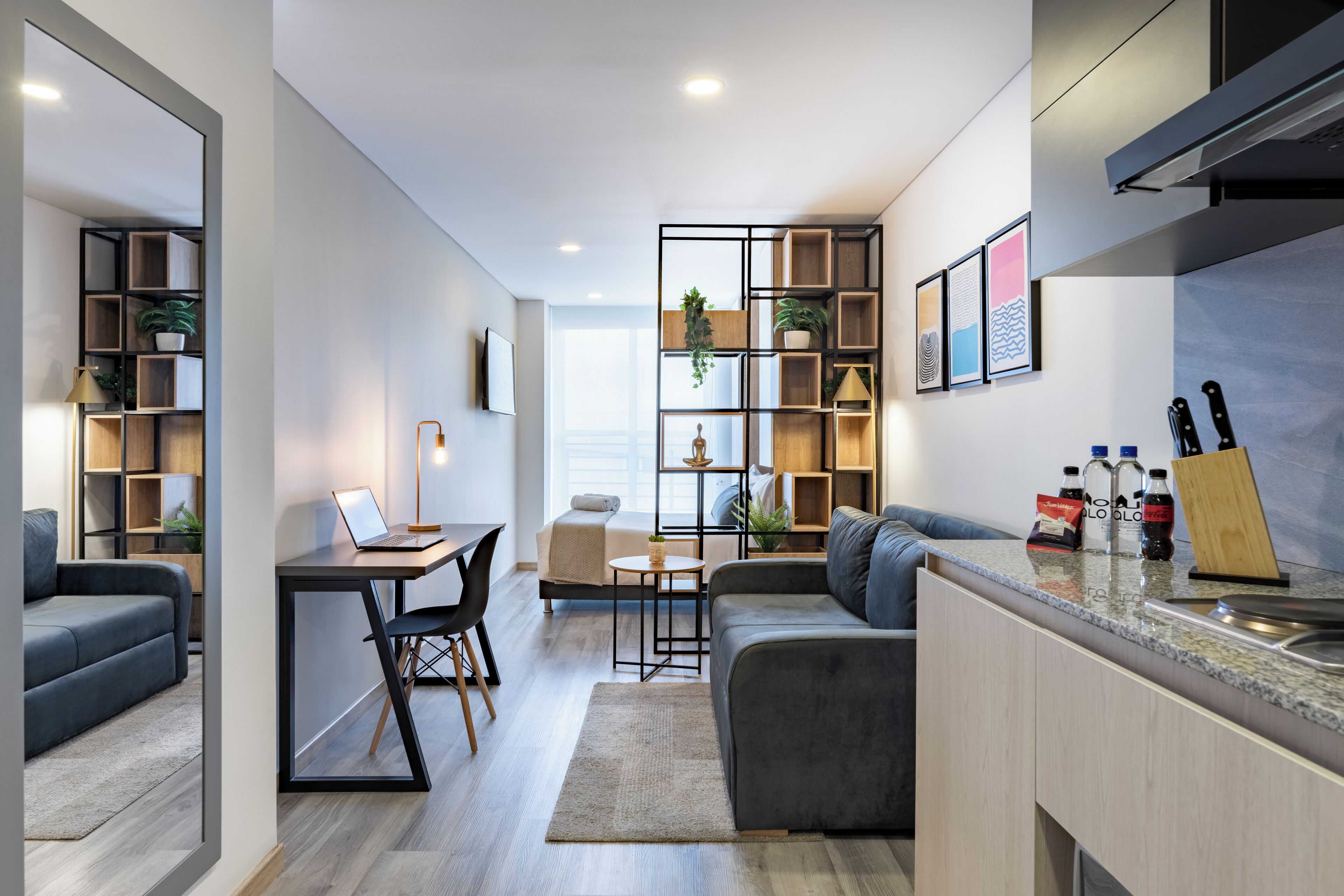A modern living space with a sofa, a dining table, and a kitchen area with a countertop and cabinets.