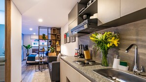A modern kitchen with a built-in stove, a sink, and a countertop. There is a dining area with a table and chairs, and a living room with a sofa and a coffee table. -  Cabrera 85-12 by Jalo (Bogotá)