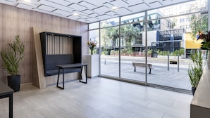 A modern reception area with a wooden panel wall, a black bench, and potted plants. -  Cabrera 85-12 by Jalo (Bogotá)