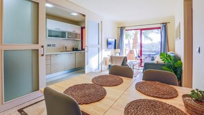Ein kompaktes Hotelzimmer mit Essbereich, Küchenzeile und Blick ins Freie.